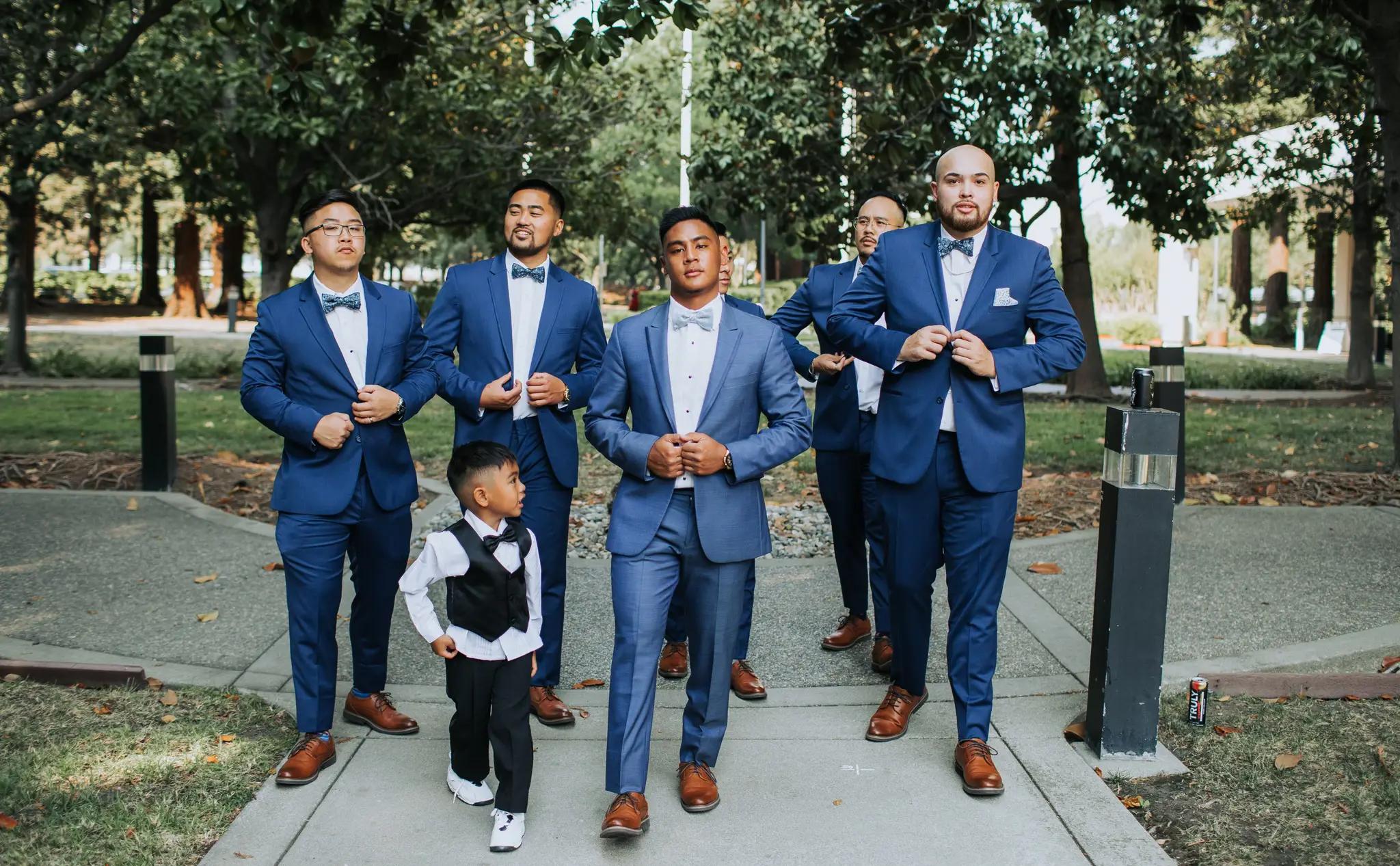 Men wearing blue suits walking with a child with black suit.